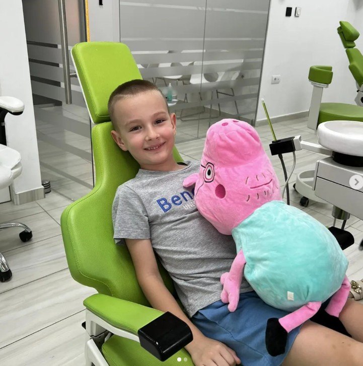 Nasmejan dečak sa plišanom igračkom u stomatološkoj stolici